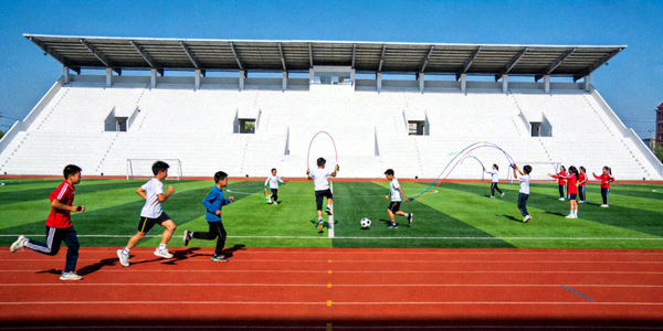 现代化学校操场，学生正在进行体育活动